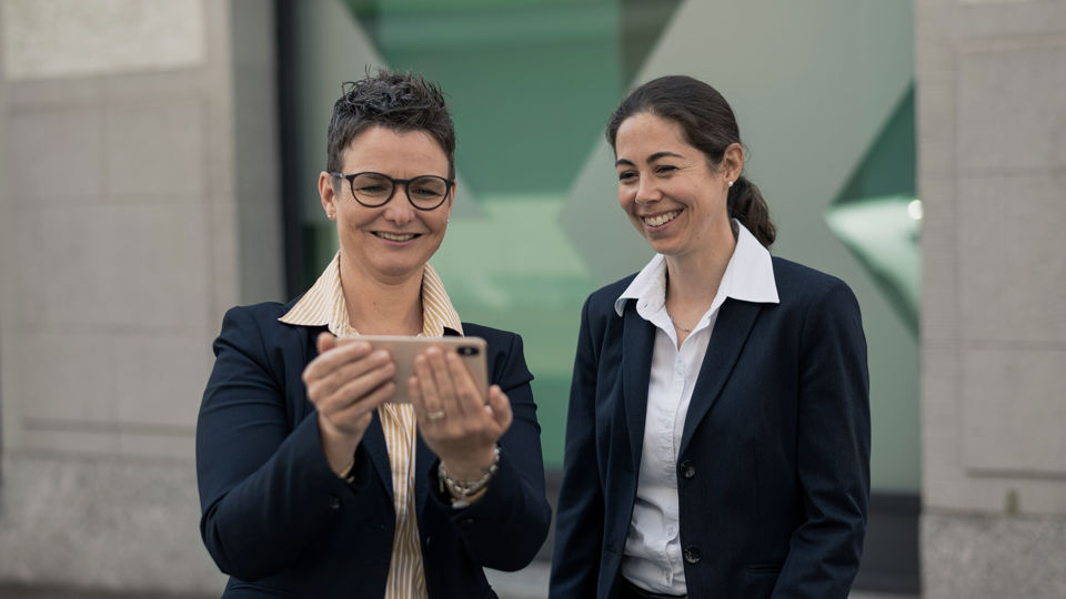 Andrea Etterlin und Doris Bartolo (Jobsharing bei der SGKB) schauen lächelnd auf ein Smartphone